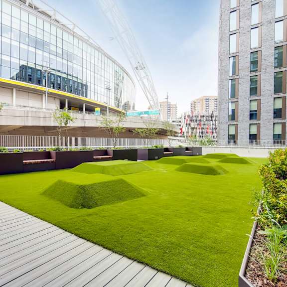 A modern building with a glass facade and a green roof garden at Beton Apartments, Wembley, HA9 0SL