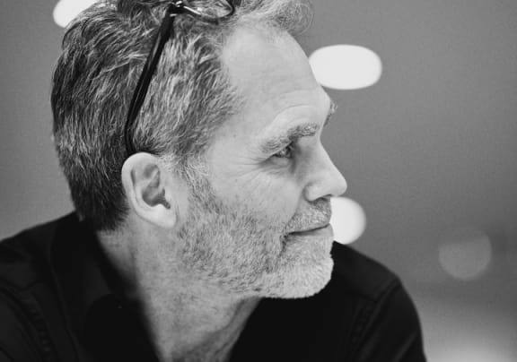 a black and white photo of a man in a black shirt with his arms crossed