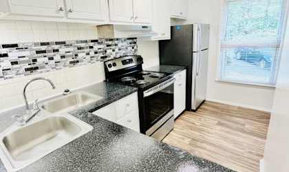 A kitchen with black countertops and white cabinets.at Twin City Townhomes, Winston-Salem