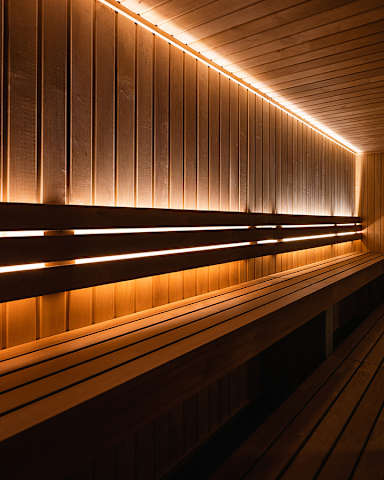 A row of wooden benches are lined up under a row of lights.