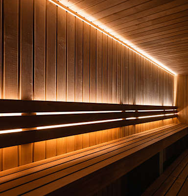 A row of wooden benches are lined up under a row of lights.