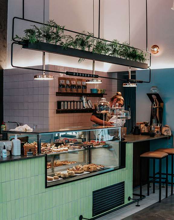 A bakery interior with a green counter and a person working behind the counter.