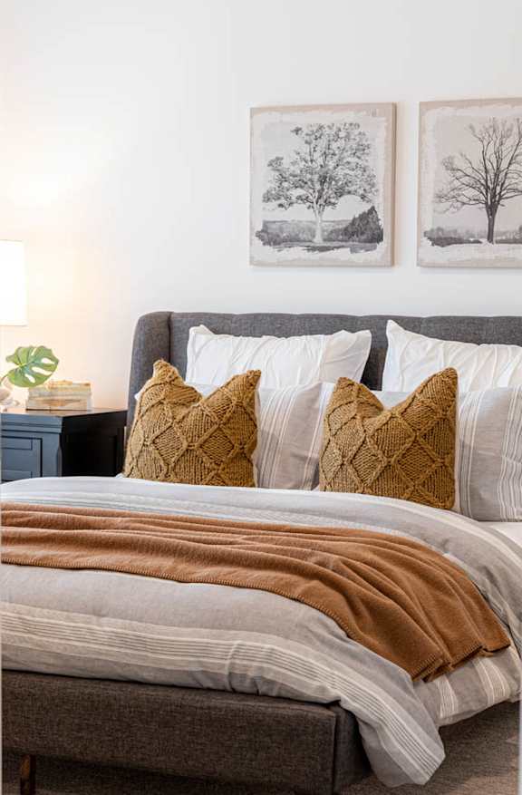 a bedroom with a bed and pillows and pictures on the wall