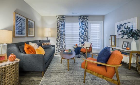 a living room with a gray couch and orange and blue chairs