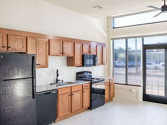 A kitchen with black appliances and wooden cabinets.