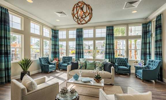 a living room with couches and chairs and large windows