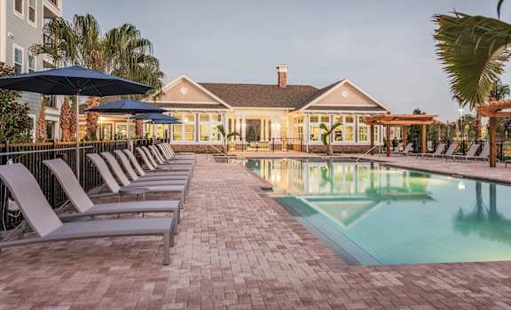 a pool with lounge chairs and a house in the background