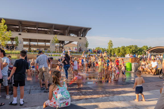 a crowd of people playing in a water fountain
