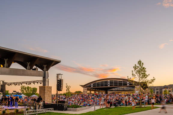 a large crowd of people watching a concert at sunset
