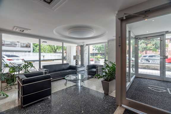 A black sofa sits in a room with a glass table and a glass door. at 177 Saint George in Toronto, CA