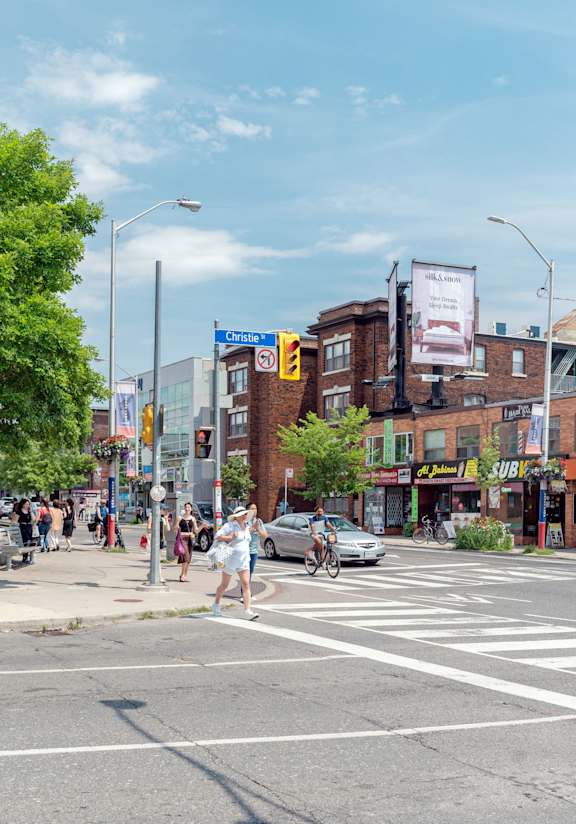 people crossing the street at a crosswalk on a busy city street at 723 Bloor Apartments, Canada