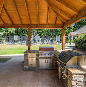 A wooden covered patio with a grill and a stone wall. at Woodwinds, South Carolina, 29803