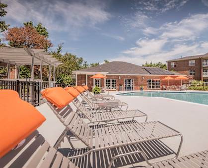 A poolside area with sun loungers and a building in the background at Jamison Park Apartments in North Charleston, SC 29406
