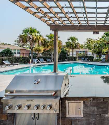 two gas bbq grills with a pool in the background