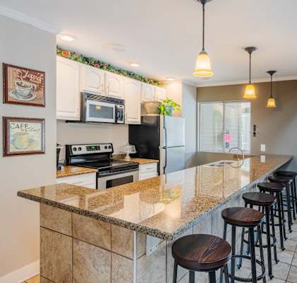 A kitchen with a granite countertop and bar stools.