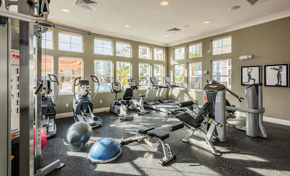 a gym with cardio equipment and windows at the district at highland village apartments