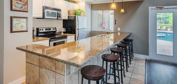 A kitchen with a granite countertop and bar stools.