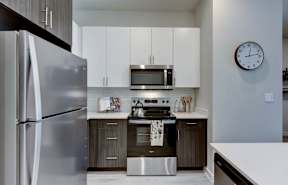 A modern kitchen with a stainless steel refrigerator and a microwave above the stove.