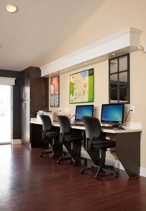 an office with a desk with computers and chairs