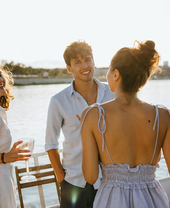 A couple standing close together on a dock with a woman holding a glass of wine. at The Grove Apartments, Orillia, L3V 1H4