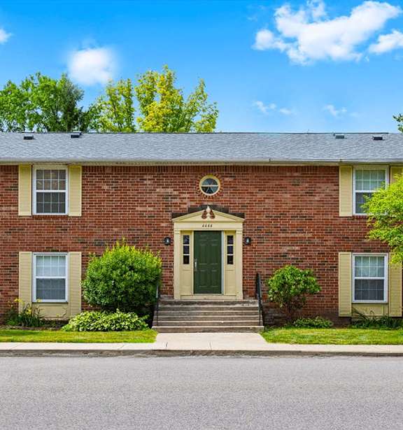 A red brick house with a green door and two windows.