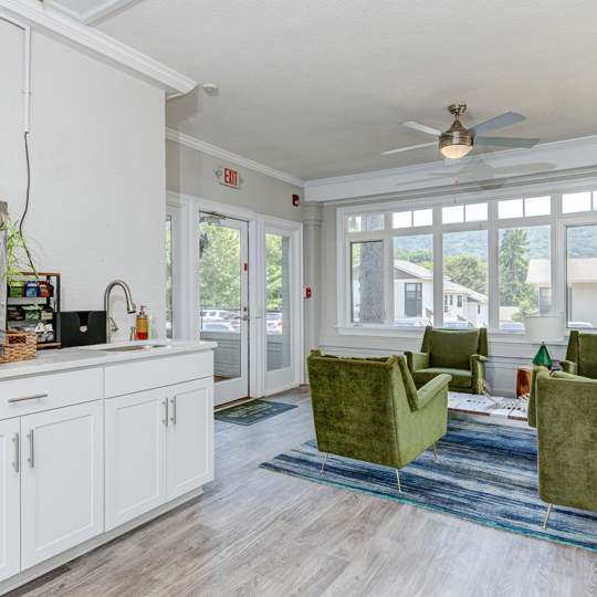 A kitchen with white cabinets and a green chair.