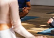 Thumbnail 9 of 10 - A group of people are sitting in a circle on yoga mats, meditating.