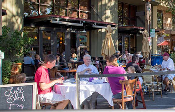 People are sitting at tables outside a restaurant.