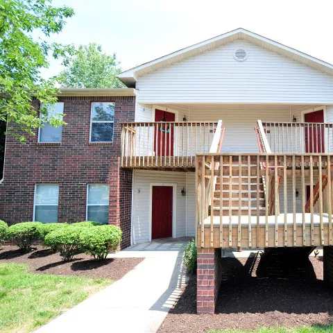A red and white house with a wooden deck.