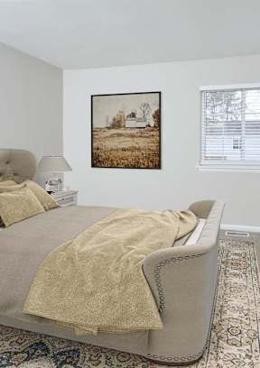 A bedroom with a large bed and a painting on the wall.