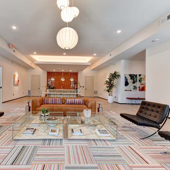 A living room with a multicolored carpet and a glass coffee table. at Bridge at Saffron, Austin, TX