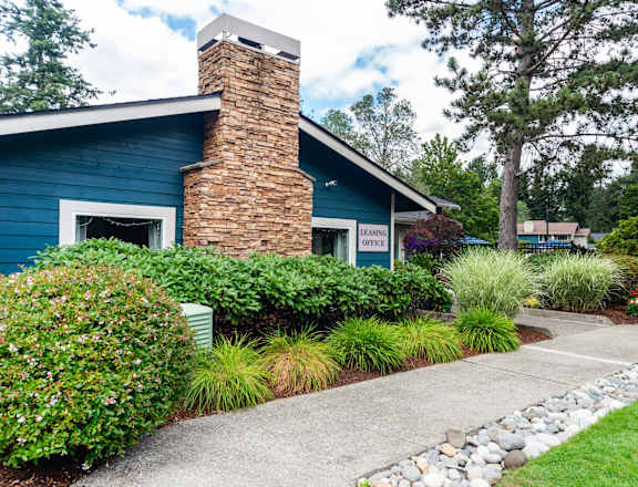 A blue house with a brick chimney and a stone pathway leading to the front door.