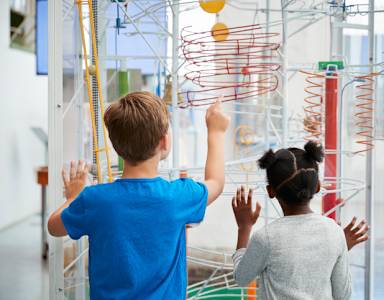 Two children playing with a spring-based toy in a room.