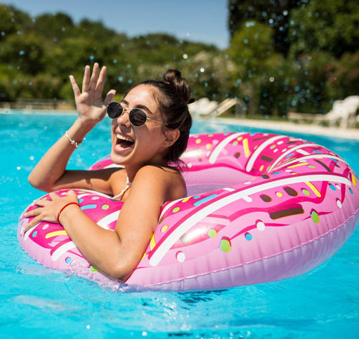 a young girl in a pool wearing sunglasses and a pink inner tube