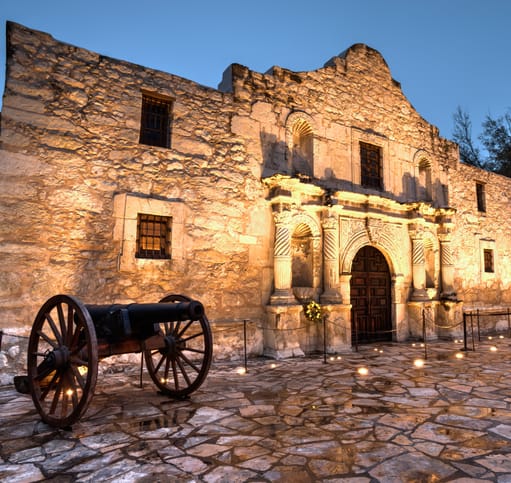 an old stone building with a cannon in front of it