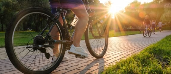 a person riding a bike down a sidewalk at sunset at Savan Pointe Townhomes East and West, Savannah, GA