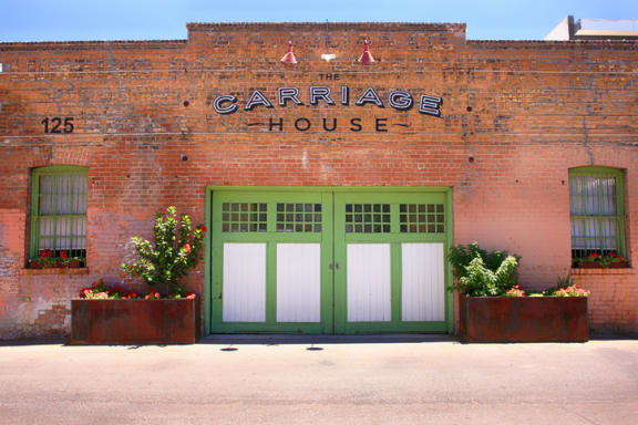 an old brick building with green doors and a sign that reads carriage house at Promontory, Tucson, AZ, 85704