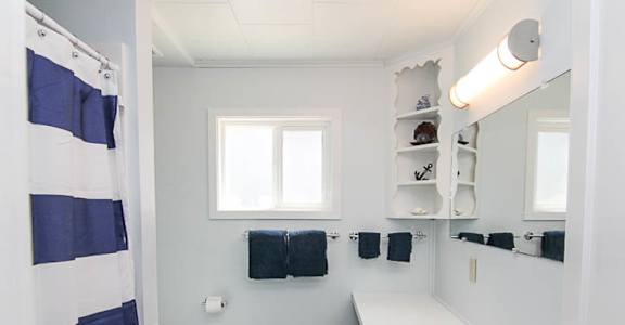 A bathroom with a white sink and a blue and white striped shower curtain.