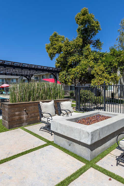 a patio with a fire pit and chairs in front of a pool