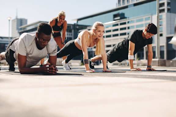 A group of people doing push-ups outdoors.