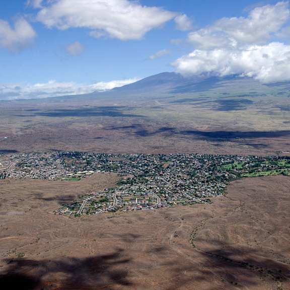 A small town is nestled in the valley of a large mountain.