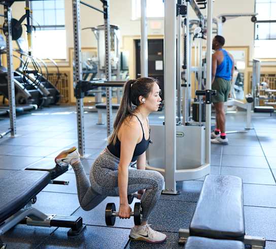 a woman sitting on a dumbbell in a gym