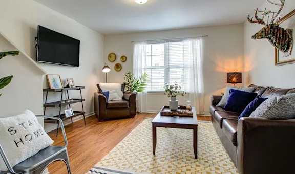 A living room with a brown couch, a coffee table, a chair, a TV, and a rug.
