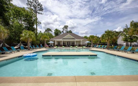 a large swimming pool with blue chairs and a house