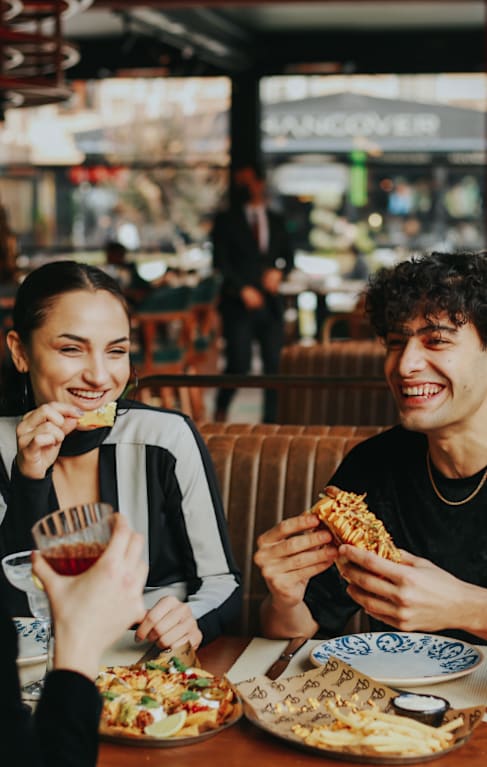 Two people eating pizza in a restaurant.