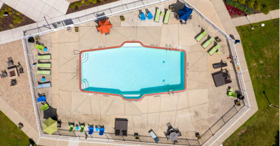 An aerial view of a swimming pool surrounded by lounge chairs and umbrellas.