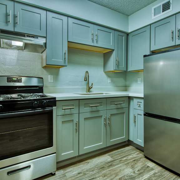 A kitchen with a stove, refrigerator, and cabinets. at The Link Apartments, Mesa, Arizona