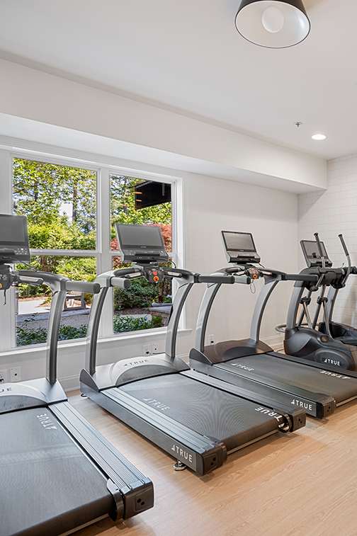 A spacious room with a mirror, exercise equipment, and a television displaying a sunset.