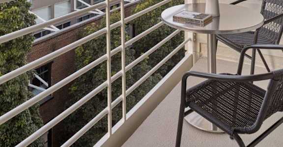 A balcony with a table and chairs overlooking a cityscape.