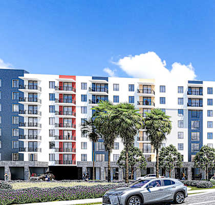 A modern multi-story building with a parking lot in front.